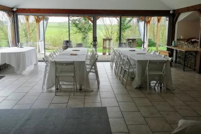 Miniature Location salle La Couyère (Ille-et-Vilaine) - La Demeure du Pont #3 Salle de réception lumineuse avec murs en pierre, tables rondes dressées de nappes blanches et décorations simples.