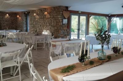 Miniature Location salle La Couyère (Ille-et-Vilaine) - La Demeure du Pont #18 Salle de réception lumineuse avec murs en pierre, tables rondes dressées de nappes blanches et décorations simples.