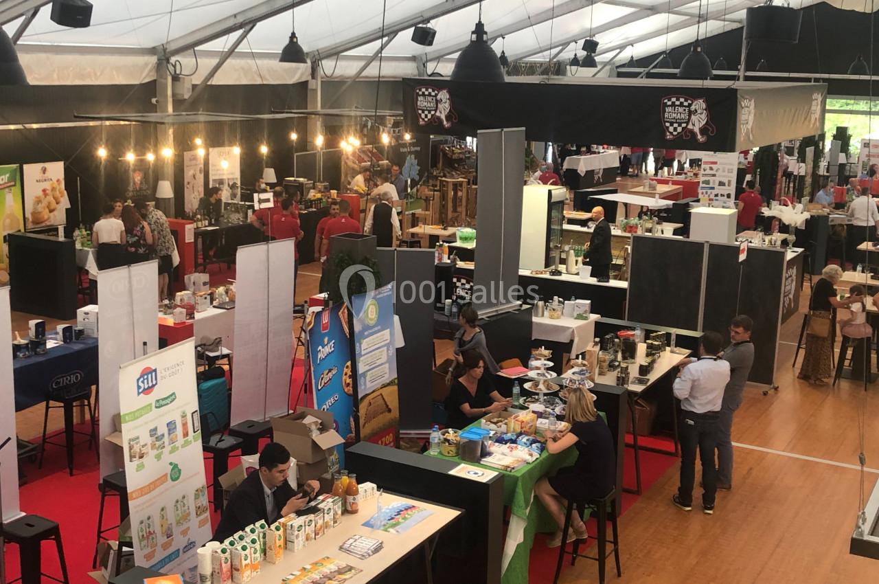 Vue d'un salon professionnel avec des stands exposant divers produits alimentaires et des visiteurs en discussion.