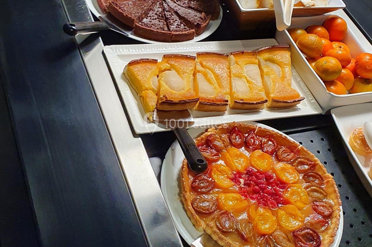Buffet de desserts variés comprenant tartes, gâteaux, fromages et fruits disposés sur un comptoir.