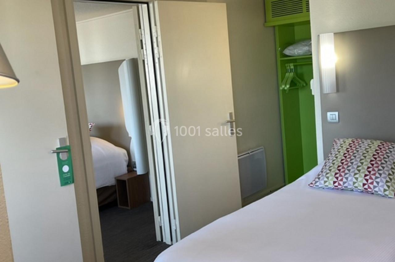 Deux chambres d'hôtel communicantes avec lits faits, penderie ouverte et décoration sobre.