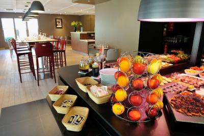 Salle de bain avec douche à paroi vitrée, lavabo suspendu, miroir éclairé et sol en carrelage foncé.