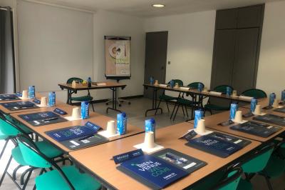 Salle de bain avec douche à paroi vitrée, lavabo suspendu, miroir éclairé et sol en carrelage foncé.