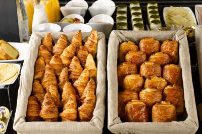 Buffet varié avec fruits frais, pâtisseries, yaourts, céréales et pots de confiture disposés sur une table.
