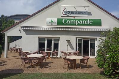 Chambre lumineuse avec un lit double, deux oreillers colorés, un bureau en bois et une lampe murale.