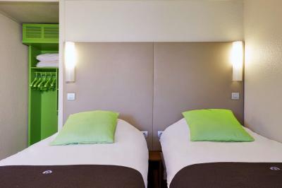 Bâtiment avec toit en tuiles, enseigne ’Campanile’, entouré de haies, d'arbustes et d'un olivier sous un ciel dégagé.