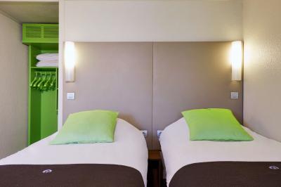 Bâtiment avec toit en tuiles, enseigne ’Campanile’, entouré de haies, d'arbustes et d'un olivier sous un ciel dégagé.