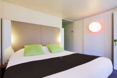 Bâtiment avec toit en tuiles, enseigne ’Campanile’, entouré de haies, d'arbustes et d'un olivier sous un ciel dégagé.