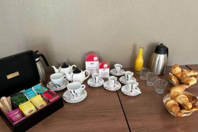 Bâtiment avec toit en tuiles, enseigne ’Campanile’, entouré de haies, d'arbustes et d'un olivier sous un ciel dégagé.