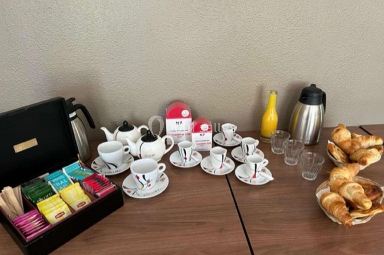 Table avec théières, tasses, assortiment de thés, carafes, verres, jus d'orange et viennoiseries.