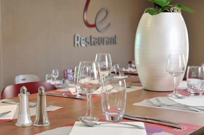 Salle de réunion avec chaises empilées, tables disposées en rangées et luminaires rouges suspendus.