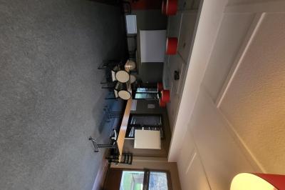 Salle de réunion avec chaises empilées, tables disposées en rangées et luminaires rouges suspendus.