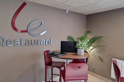Salle de réunion lumineuse avec table en bois, chaises bleues, écran mural et affichage d'accueil.