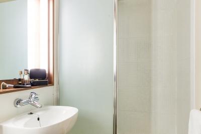 Salle de bain moderne avec lavabo, miroir, toilettes et douche vitrée sur un sol en carrelage gris.