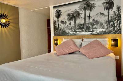 Façade d'un bâtiment à étages avec balcons bleus, partiellement cachée par un arbre sous un ciel nuageux.