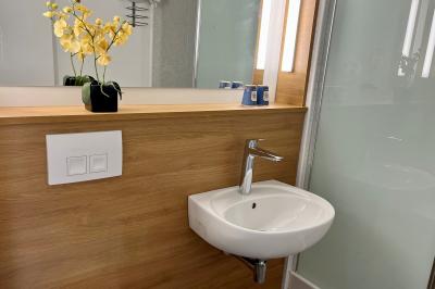 Façade d'un bâtiment à étages avec balcons bleus, partiellement cachée par un arbre sous un ciel nuageux.