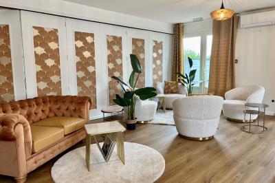 Façade d'un bâtiment à étages avec balcons bleus, partiellement cachée par un arbre sous un ciel nuageux.