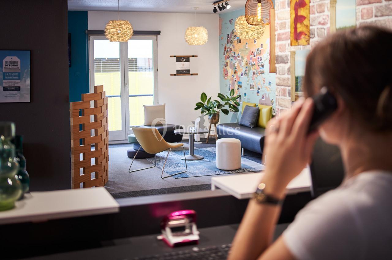 Une personne au téléphone à un comptoir, avec en arrière-plan un salon moderne et coloré.