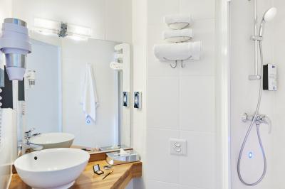 Chambre d'hôtel avec lit double, bureau équipé, lampe allumée et fenêtre avec rideaux marron.