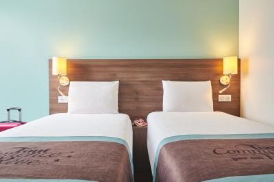 Chambre d'hôtel avec lit double, bureau équipé, lampe allumée et fenêtre avec rideaux marron.