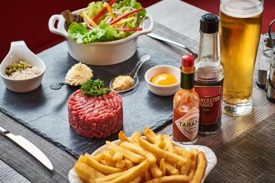 Chambre d'hôtel avec lit double, bureau équipé, lampe allumée et fenêtre avec rideaux marron.
