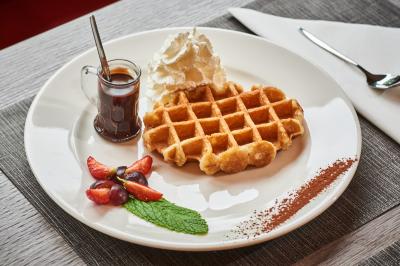 Chambre d'hôtel avec lit double, bureau équipé, lampe allumée et fenêtre avec rideaux marron.