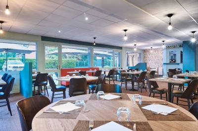 Chambre d'hôtel avec lit double, bureau équipé, lampe allumée et fenêtre avec rideaux marron.