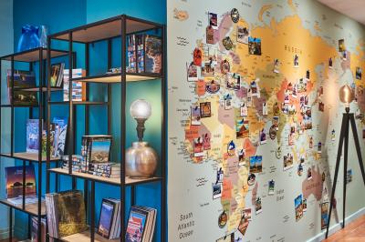 Chambre d'hôtel avec lit double, bureau équipé, lampe allumée et fenêtre avec rideaux marron.