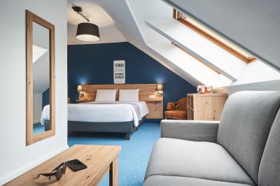 Chambre d'hôtel avec lit double, bureau équipé, lampe allumée et fenêtre avec rideaux marron.