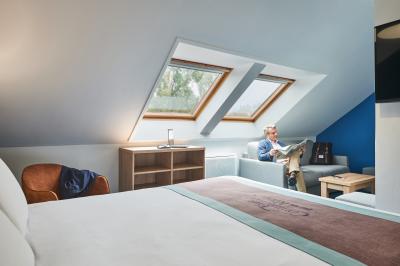 Chambre d'hôtel avec lit double, bureau équipé, lampe allumée et fenêtre avec rideaux marron.