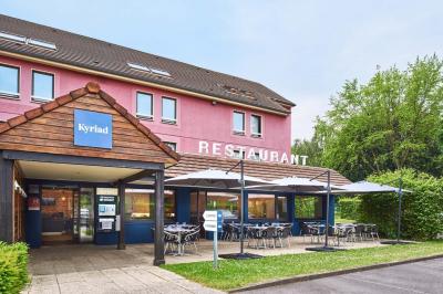 Chambre d'hôtel avec lit double, bureau équipé, lampe allumée et fenêtre avec rideaux marron.