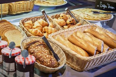 Chambre d'hôtel avec lit double, bureau équipé, lampe allumée et fenêtre avec rideaux marron.
