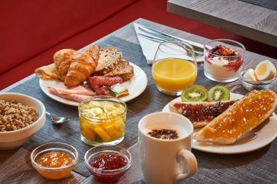 Chambre d'hôtel avec lit double, bureau équipé, lampe allumée et fenêtre avec rideaux marron.