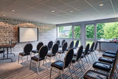 Chambre d'hôtel avec lit double, bureau équipé, lampe allumée et fenêtre avec rideaux marron.
