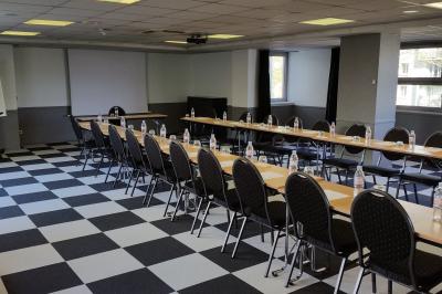 Salle de réunion avec tables disposées en U, bouteilles d'eau, stylos et blocs-notes sur chaque place.