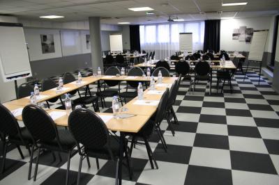 Salle de réunion avec tables disposées en U, bouteilles d'eau, stylos et blocs-notes sur chaque place.