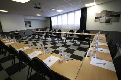 Salle de réunion avec tables disposées en U, bouteilles d'eau, stylos et blocs-notes sur chaque place.
