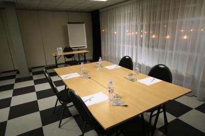 Salle de réunion avec tables disposées en U, bouteilles d'eau, stylos et blocs-notes sur chaque place.