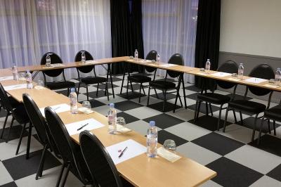 Salle de réunion avec tables disposées en U, bouteilles d'eau, stylos et blocs-notes sur chaque place.
