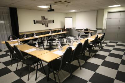 Salle de réunion avec tables disposées en U, bouteilles d'eau, stylos et blocs-notes sur chaque place.