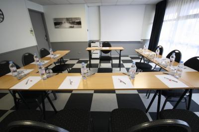 Salle de réunion avec tables disposées en U, bouteilles d'eau, stylos et blocs-notes sur chaque place.