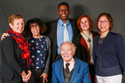Un groupe de personnes pose devant une bannière, une femme au centre tient un diplôme.