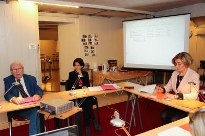 Un groupe de personnes pose devant une bannière, une femme au centre tient un diplôme.
