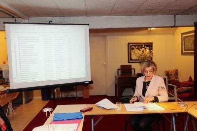 Un groupe de personnes pose devant une bannière, une femme au centre tient un diplôme.