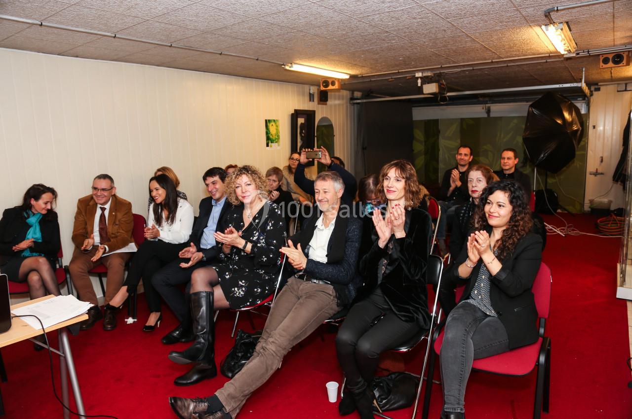 Un groupe de personnes assises dans une salle, applaudissant et regardant vers l'avant.