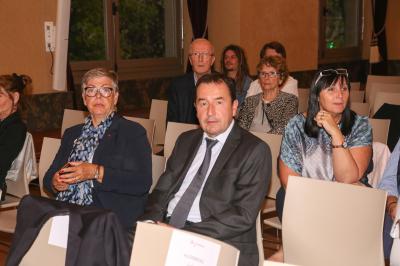 Un groupe de personnes pose devant une bannière, une femme au centre tient un diplôme.