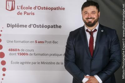 Un groupe de personnes pose devant une bannière, une femme au centre tient un diplôme.