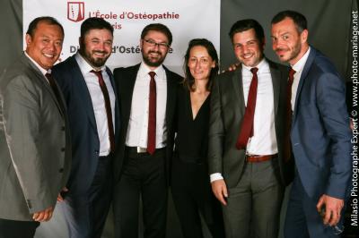 Un groupe de personnes pose devant une bannière, une femme au centre tient un diplôme.
