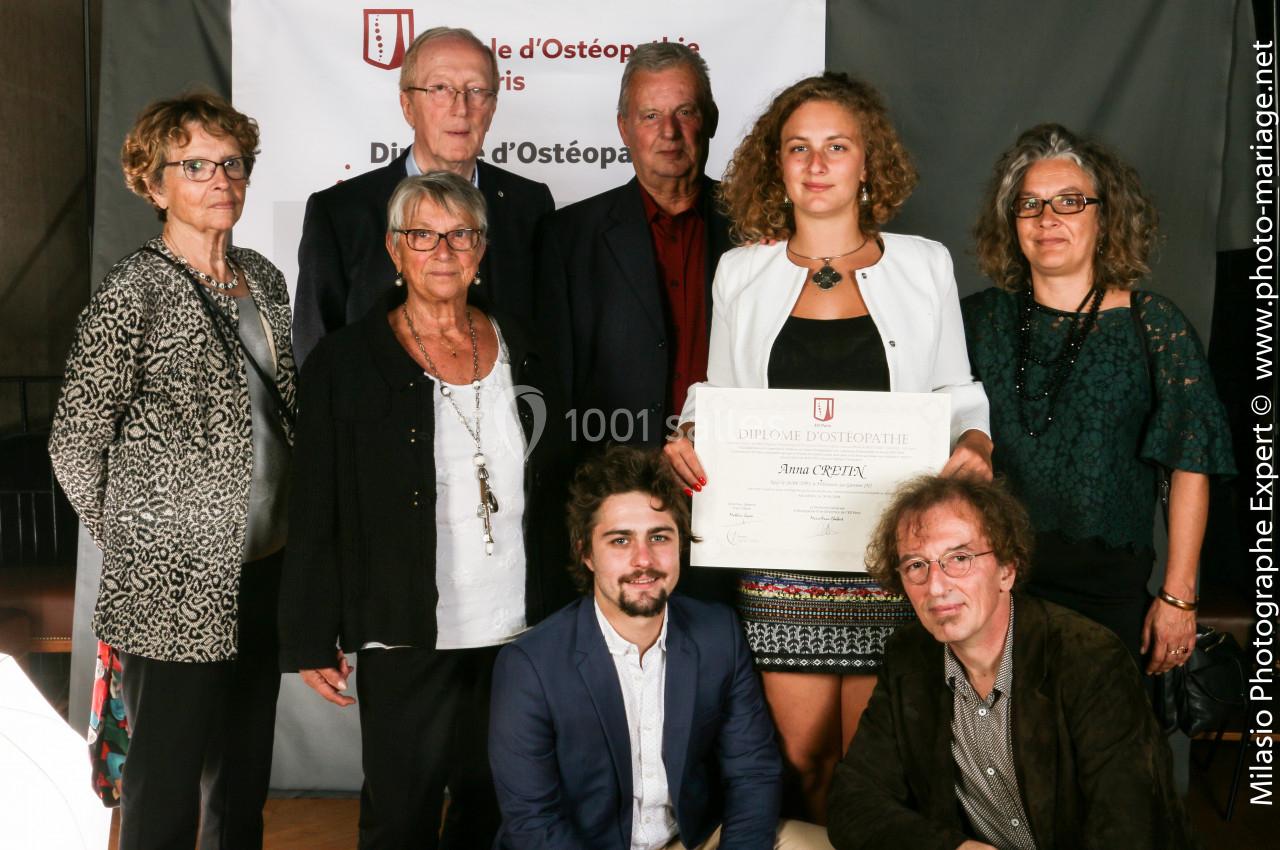 Un groupe de personnes pose devant une bannière, une femme au centre tient un diplôme.
