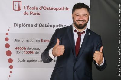 Un groupe de personnes pose devant une bannière, une femme au centre tient un diplôme.